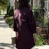 Woman in a brown dress walking on a sidewalk with a building in the background